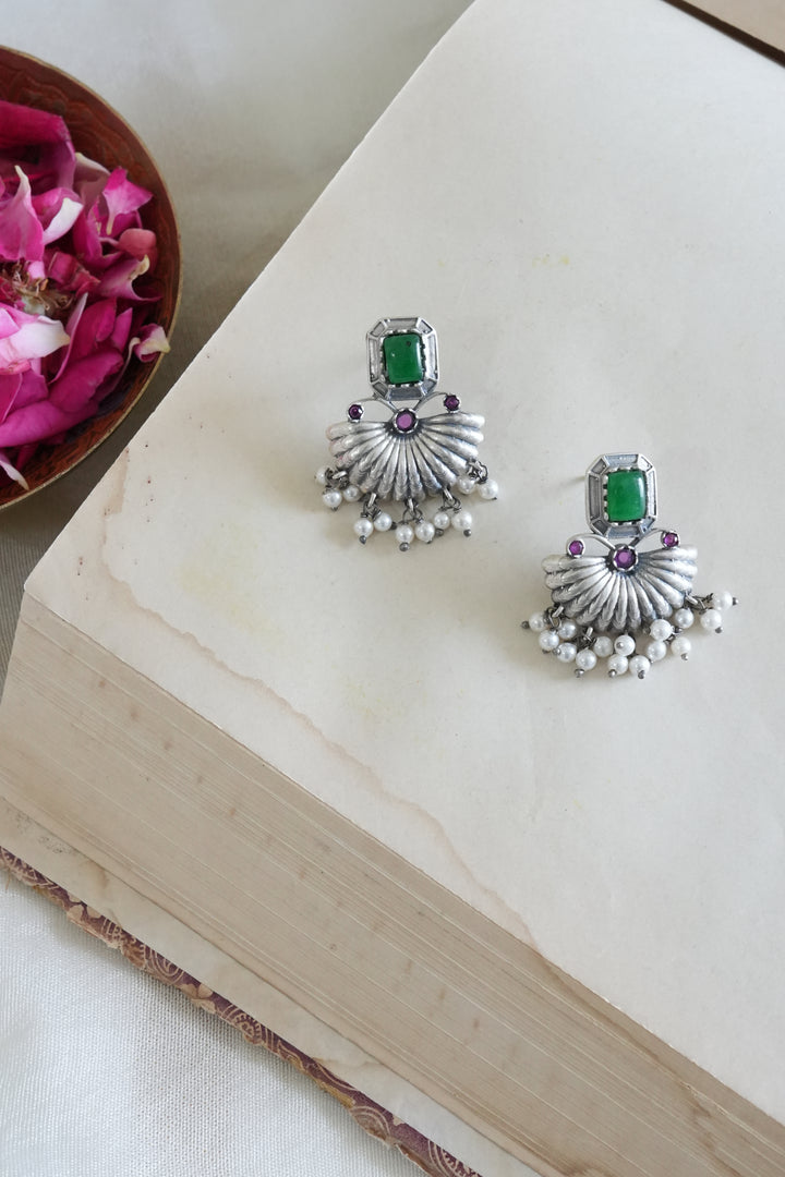 Silver earrings with green gemstones on a white surface